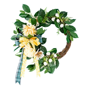 Handmade artificial Christmas wreath with yellow dahlias and green leaves on rattan base