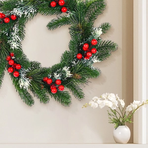 Christmas pine needle wreath with red berries and snow-flocked leaves for door decor