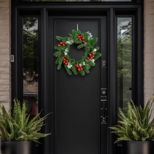 Christmas pine needle wreath with red berries and snow detail hanging on a black door