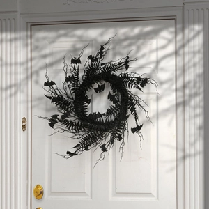 Halloween black wreath with bat ornaments and artificial branches on a white door