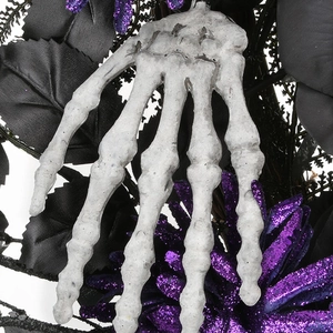 Halloween wreath featuring aged skeleton hand with purple glitter flowers and black leaves