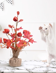 Dettaglio di un albero di acero artificiale con bacche, base in iuta e un gatto bianco