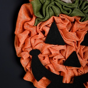 Handmade burlap pumpkin wreath for Halloween party door decor with felt face details