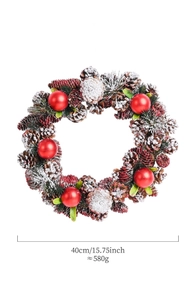 Detail of a 40cm Christmas wreath with pine cones and red balls featuring snow-flecked texture