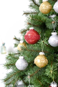 Details von roten und goldenen Weihnachtskugeln mit Glitzerbändern an einem Tannenbaum