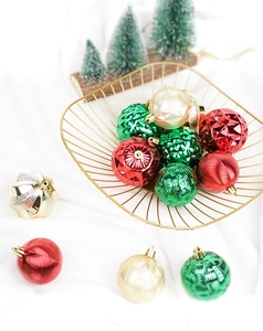 Detailed view of red, green, and gold textured Christmas baubles in a metal wire basket