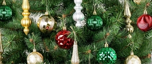 Close-up of assorted red, gold and green textured Christmas ornaments on pine branches