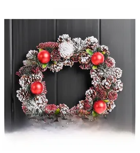 Detailed view of Christmas wreath with pine cones and red ornaments on wood