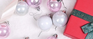 Pink and white Christmas ball ornaments on white faux fur with a festive gift box decor