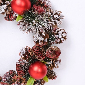 Christmas wreath with pine cones, red baubles and artificial snow for holiday door decor