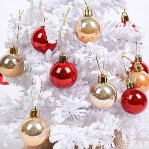 Detail of glossy red and gold Christmas balls hanging on a white flocked tree branch