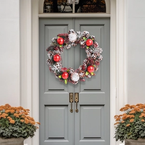 Christmas wreath with pine cones and red ornaments on a front door for festive decor