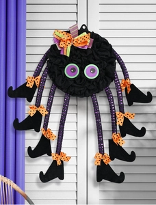 Detail of Halloween spider wreath with purple striped legs and orange bows on white shutter