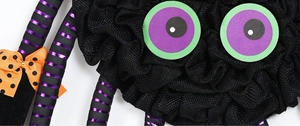 Macro detail of Halloween plush spider with orange bow and mesh texture for party decor