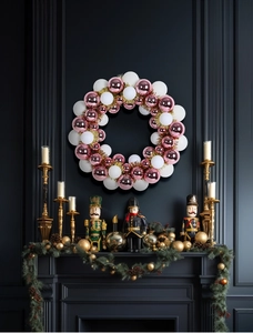 Pink and white Christmas ball wreath displayed on a black mantle with festive decor