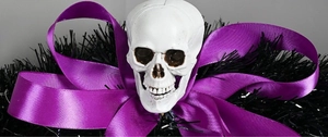 Macro detail of Halloween wreath showing a white skull and large purple ribbon bow decoration
