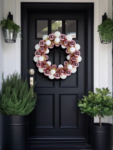 Pink and white Christmas ball wreath hanging on a modern black front door entry