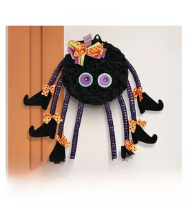 Detail of Halloween spider wreath with purple eyes and witch boot legs hanging on wall