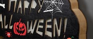 Macro detail of lighted Happy Halloween wooden door sign with pumpkin and spider motifs