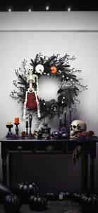Close-up of Halloween wreath with black twigs, purple glitter, pumpkin, and a skeleton doll
