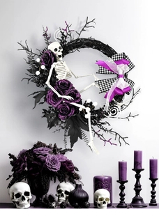Dettaglio ghirlanda Halloween con scheletro, rose viola e foglie nere su parete bianca
