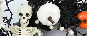 Detail of Halloween wreath featuring white skull, orange pumpkin and black glitter twigs