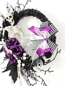 Dettaglio ghirlanda di Halloween con rose viola glitterate, teschi e fiocchi in pied-de-poule