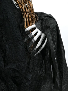 Détail de déco Halloween avec main de squelette tenant de la gaze noire et des brindilles