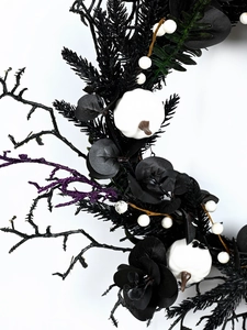 Detail of gothic Halloween wreath with black leaves, white pumpkins and purple glitter stems