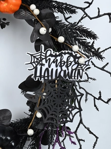 Detail of Halloween wreath with orange pumpkin, black twigs, and Happy Halloween sign