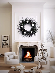Detail of black Halloween wreath with white pumpkins over a fireplace with flames