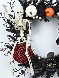 Detail of Halloween wreath with skeleton, black pine needles and assorted pumpkins