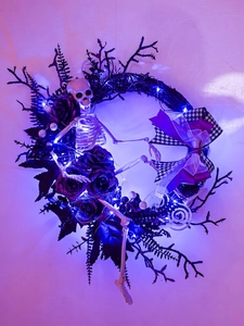 Dettaglio ghirlanda Halloween con LED blu, rose viola e scheletro bianco decorativo