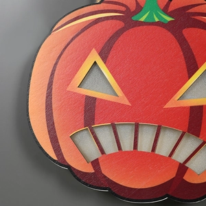 Close-up of wooden pumpkin hanging decoration with silver glitter details for Halloween