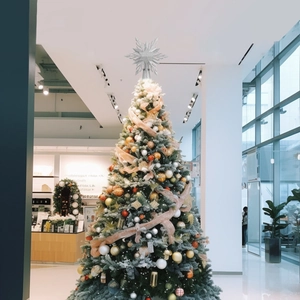 Close-up of a silver glitter star topper on a snow-flocked Christmas tree decorated with gold baubles