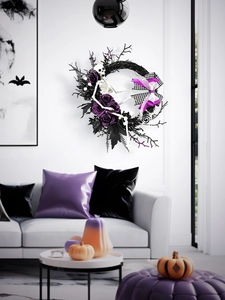 Dettaglio ghirlanda di Halloween con rose viola, bacche nere e scheletro sulla parete