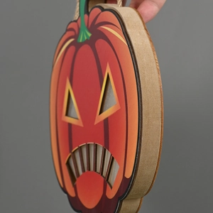 Detail of wooden Halloween pumpkin door hanger with glowing cutouts and rustic twine rope