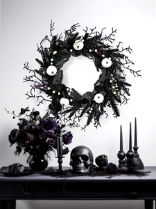 Macro detail of gothic Halloween wreath featuring white pumpkins and black pine needles