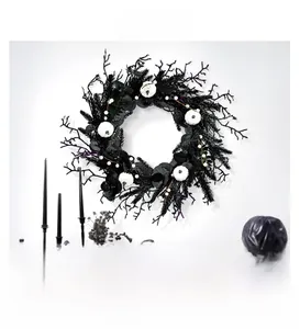 Detail of black Halloween wreath with white pumpkins and pine needles on a white wall