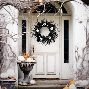 Gothic Halloween wreath with black branches and white pumpkins on a white door