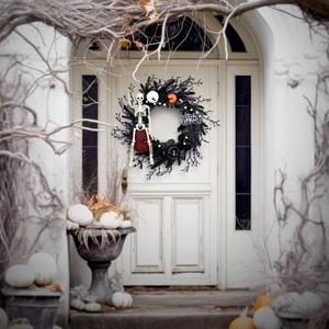 Halloween wreath featuring black vines, skulls, and pumpkins on a white front door