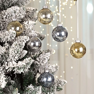 Metallic gold and silver Christmas ball ornaments on flocked tree with bokeh lights