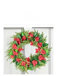 Close-up of artificial red berries and pine needles on a festive holiday wreath hanging on a white door