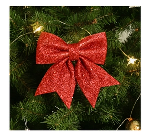 Macro shot of a red glitter Christmas bow hanging on a green tree with warm LED lights
