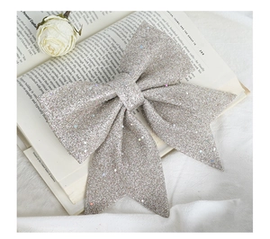 Detail of large silver glitter Christmas bow with sequins on a vintage book