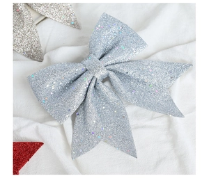Close-up of a silver glitter Christmas bow with sequins on white fabric background