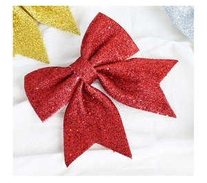Close-up of red glitter Christmas bow ornament on white textured fabric background