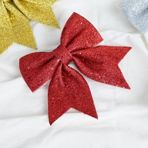 Sparkling red glitter Christmas bow ornament on white fabric for holiday tree decoration