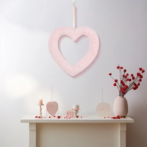 Light pink heart-shaped wreath hanging on a white wall for Valentine party decoration