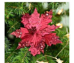 Detail of red poinsettia flower with sequins on a Christmas tree with warm lights